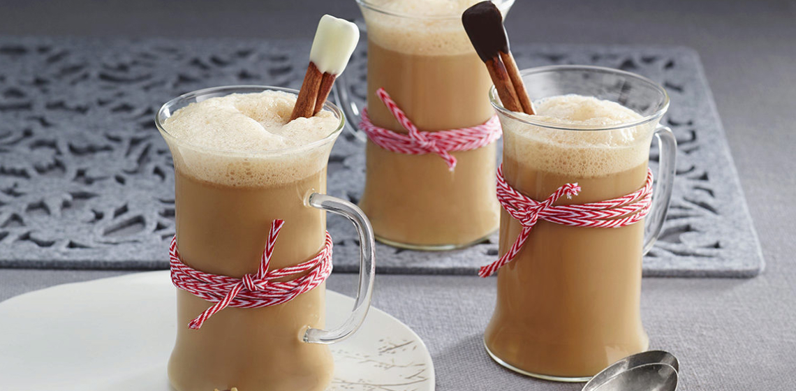 Three glass mugs filled with Gingerbread Almond Latte with a cinnamon stick poking out of the mug that’s been wrapped with red and white twine.