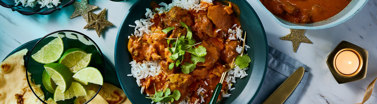 Plate of chicken tikka masala on a bed of rice with a side of naan.