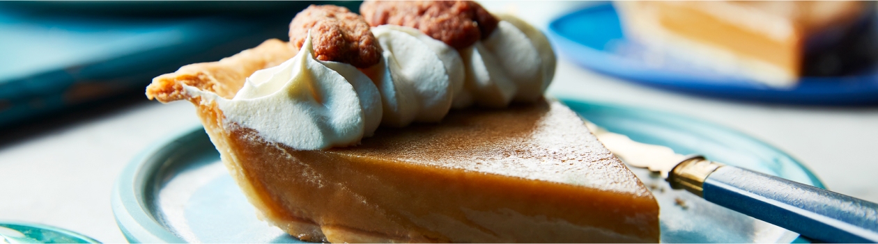 Single slice of classic Tarte au Sucre on a blue plate with whipped cream and praline pecan garnish along the crust