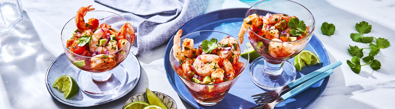 three serving glasses of Spanish-inspired Shrimp Cocktail with lime wedges