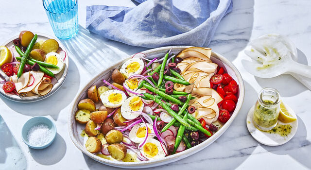 platter of niçoise salad with beans, hard-boiiled eggs, potatoes, radish, tomatoes, olives and cured meats