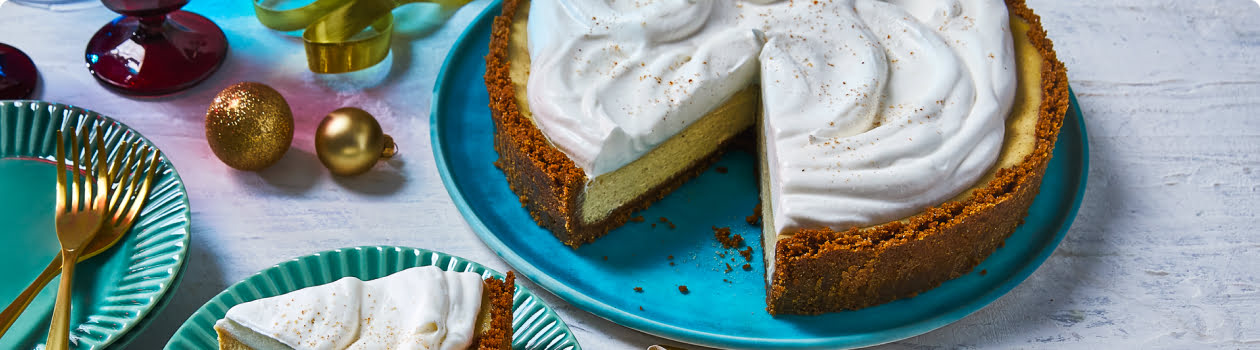 Eggnog cheesecake on blue plate with slice cut out and placed on a plate