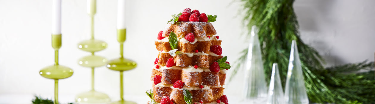 Stacked panettone with raspberries and a sprinkle of icing sugar on a plate