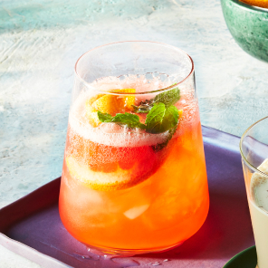 Blood orange spritz in a stemless wine glass on a purple serving tray