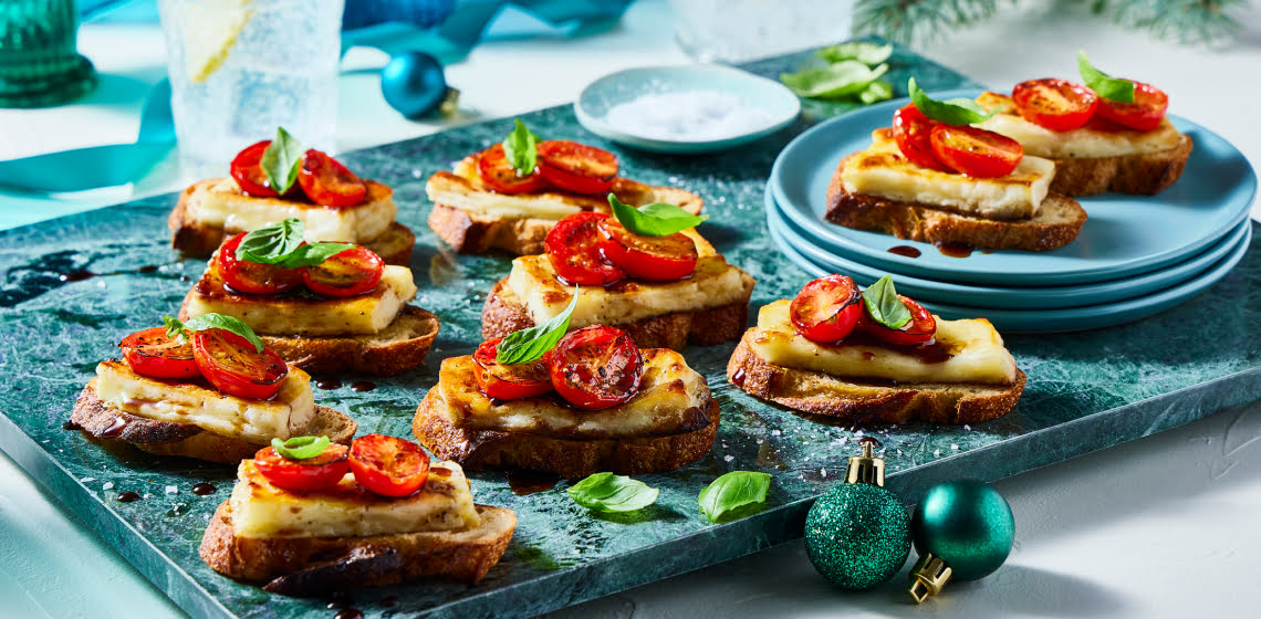 Caprese halloumi crostini on a turquoise board