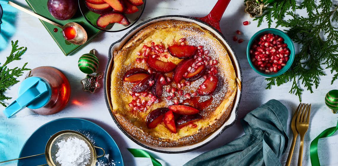 Overhead shot of Dutch Baby topped with pomegranates and plums