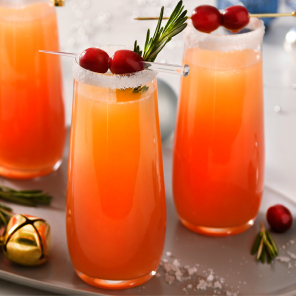 Four glasses of festive mimosa on a grey plate