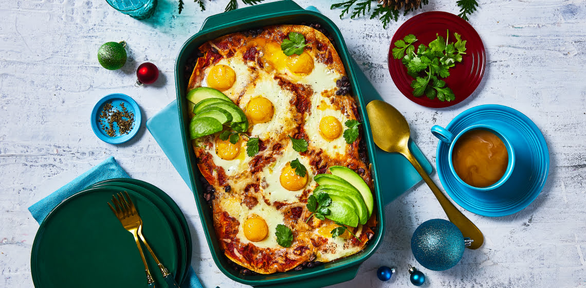 Overhead shot of huevos rancheros in a casserole dish topped with avocado.