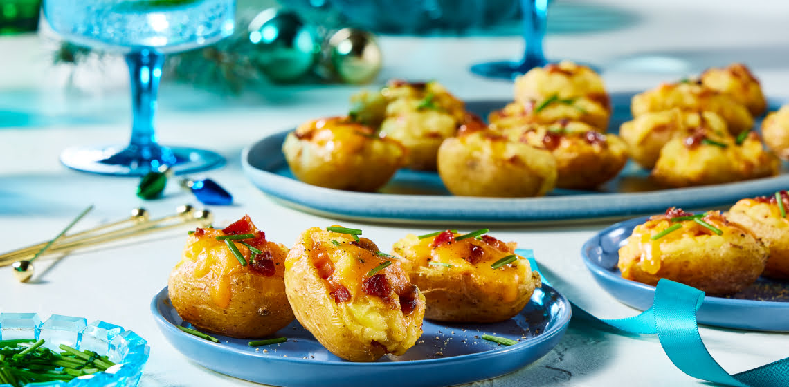 Plate of 3 mini loaded baked potato on a blue plate with a platter in the background