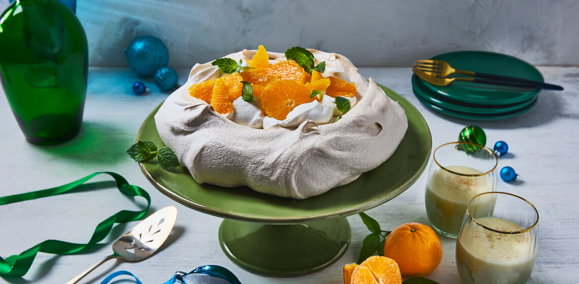 Eggnog pavlova on green plate topped with clementines and mint