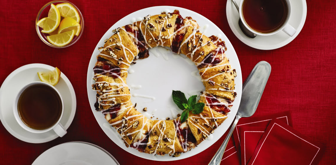 Overhead shot of strawberry-lemon crescent roll wreath on a red background