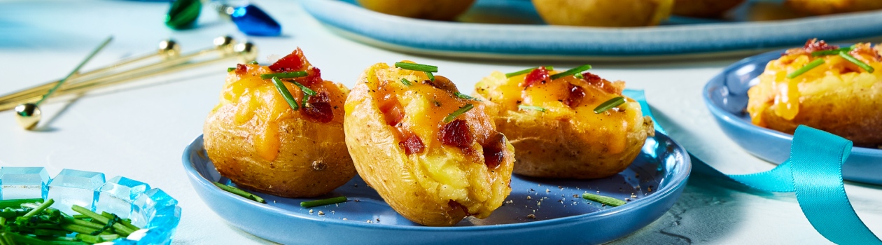 Plate of 3 mini loaded baked potato on a blue plate with a platter in the background