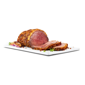 A beef sirloin tip roast royale with two pieces sliced off on a board with herbs and cooked onion