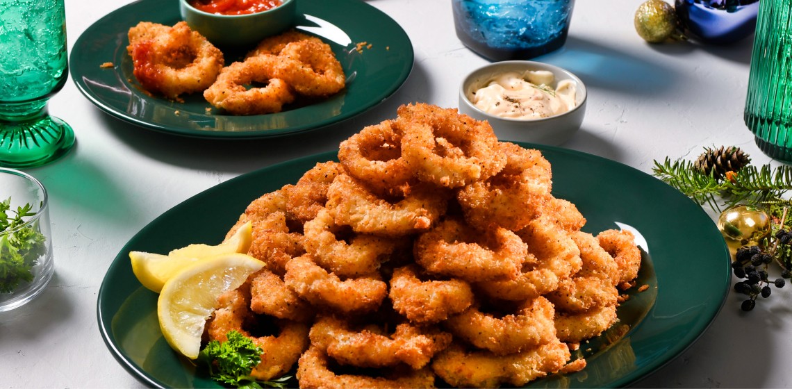 A calamari tower and lemon wedges on a green plate