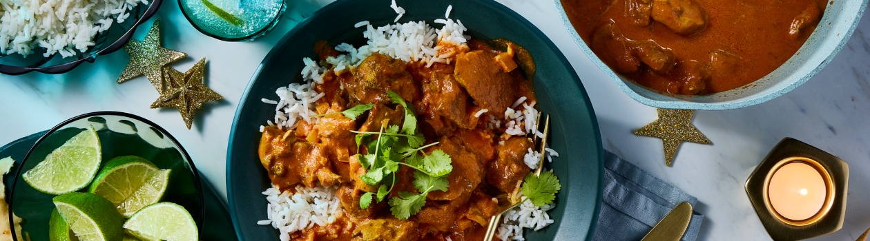 Plate of chicken tikka masala on a bed of rice with a side of naan.