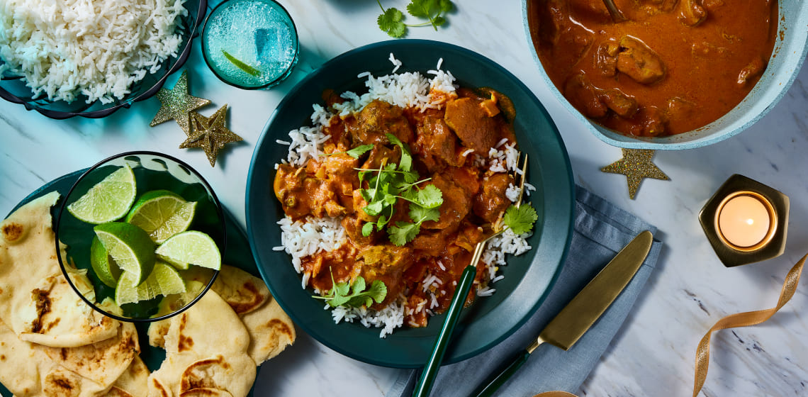  Plate of chicken tikka masala on a bed of rice with a  side of naan