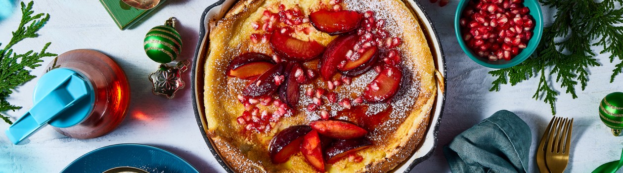 Overhead shot of Dutch Baby topped with pomegranates and plums