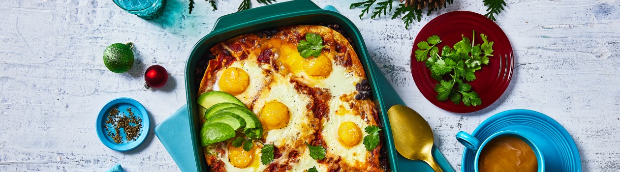 Overhead shot of huevos rancheros in a casserole dish topped with avocado.