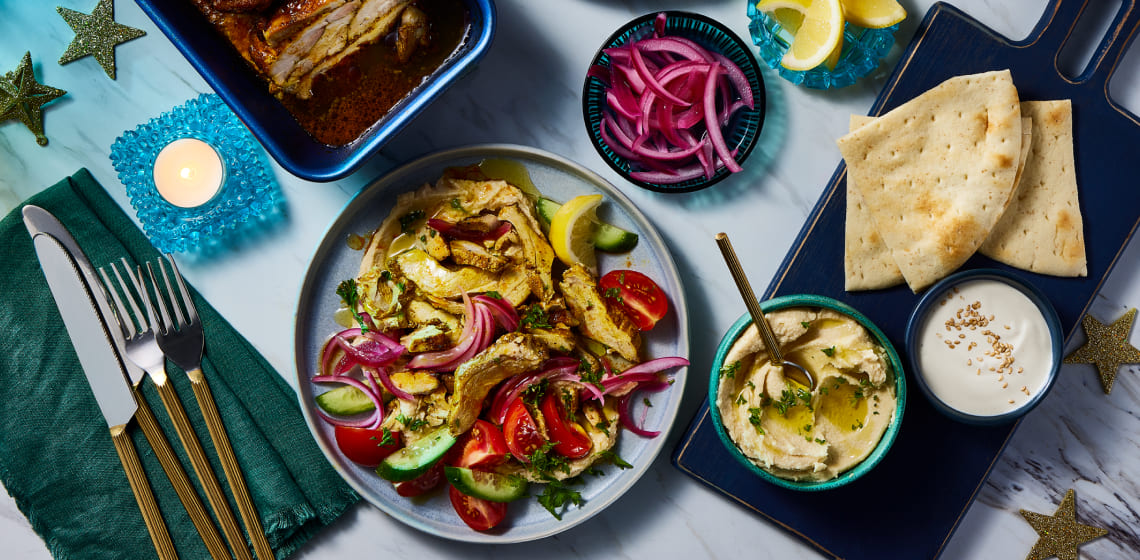 Chicken shawarma on a plate with tomatoes, onion and cucumber slices. Loaf pan beside