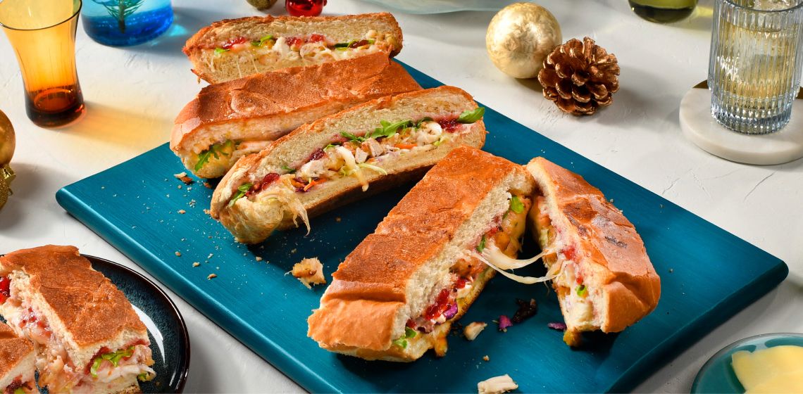 A cut up Whole Festive Chicken Dagwood sandwich on a blue serving plate