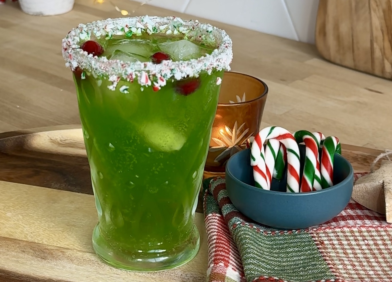 Mean green cocktail in glass with peppermint rim and candy canes in plate beside glass