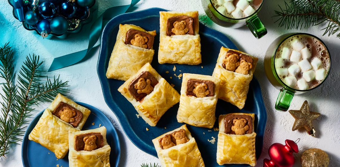 Puff pastry filled with chocolate and teddy cookies on a platter with cups of hot chocolate on to the side