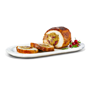 A turkey roast stuffed with pork, cranberry, and apple stuffing on a long oval plate with fresh cranberry and herb sprigs