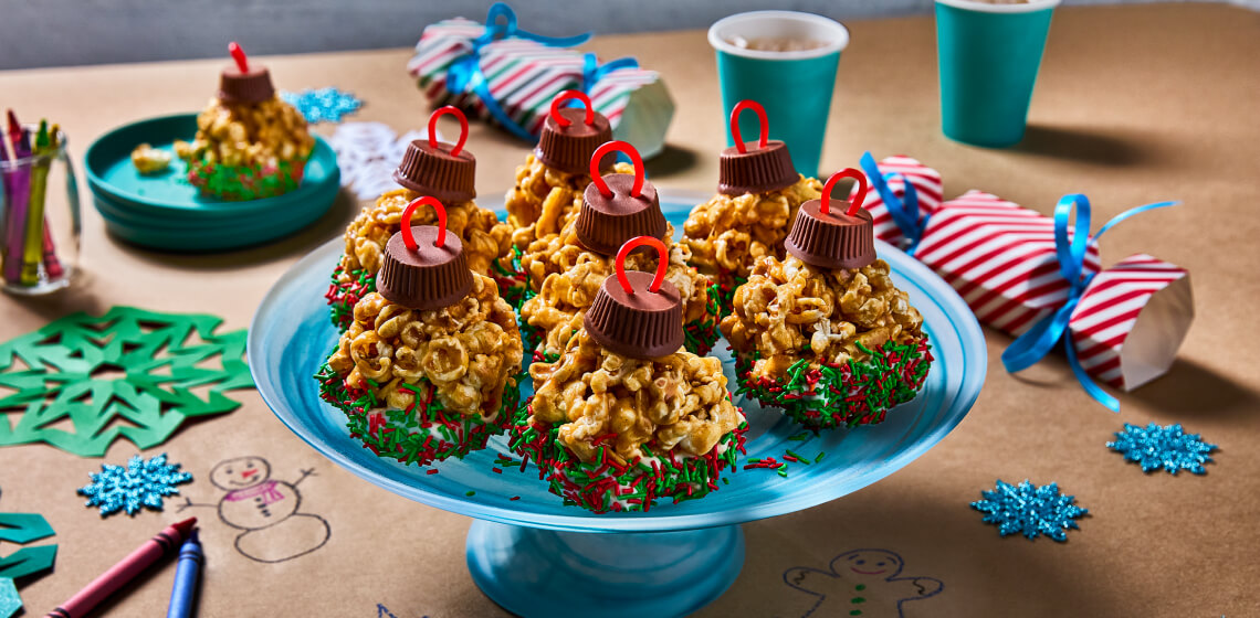 Popcorn holiday ornaments with green and red sprinkles sitting on a blue tray