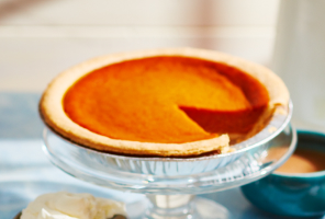 Pumpkin pie on tray with slice cut out.