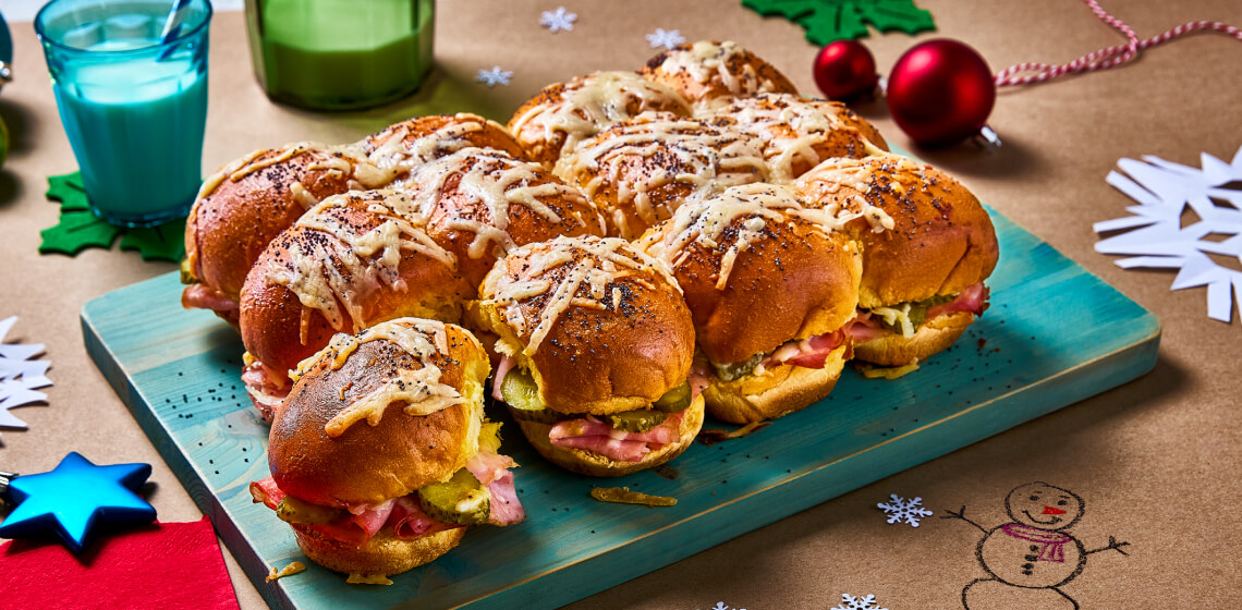  Pull apart ham and cheese sliders on a blue board with crafts in background