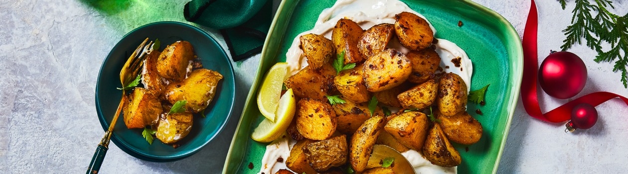 Piri Piri potatoes on a green serving platter with bowl of one serving on the side