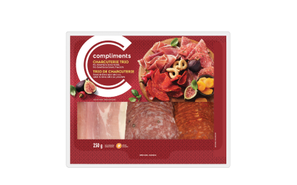 Clear plastic package of Compliments Charcuterie Trio (Dry-Cured Spicy Genoa Salami, Dry-Cured Genoa Salami & Prosciutto) with red label.