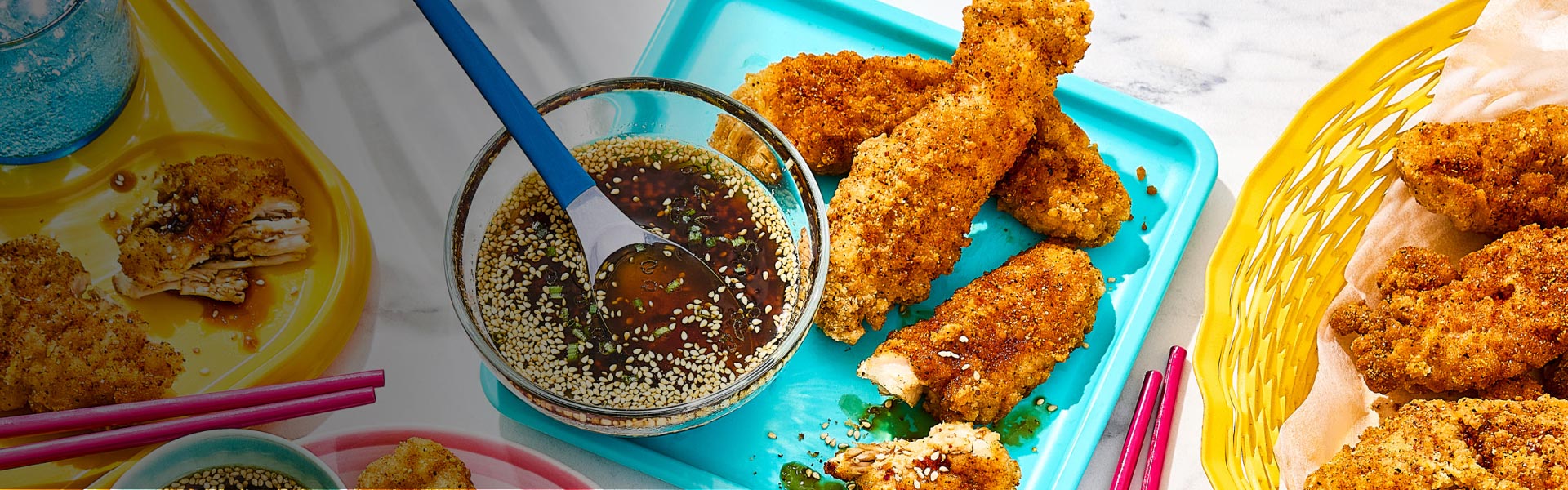 Korean chicken strips on turquoise plate with dip to the side.