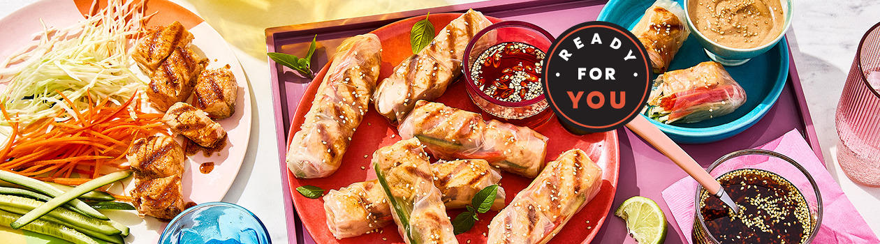 Salmon spiedini rolled in Vietnamese rice paper with veggies and dip on the side.