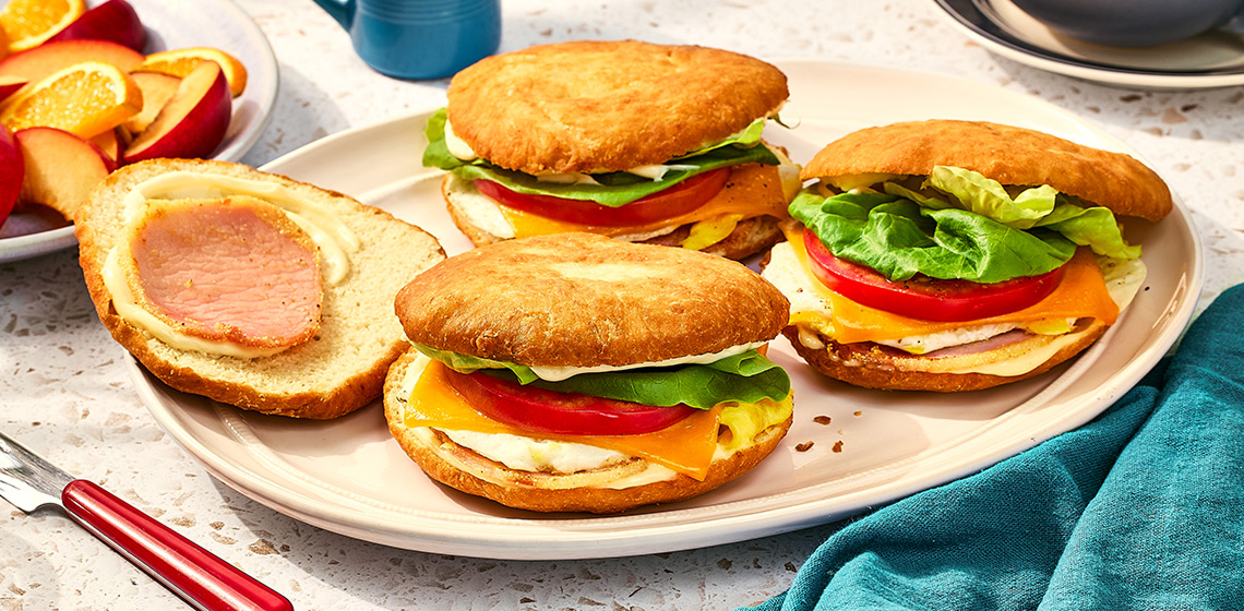 Three bannock breakfast sandwiches and a bannock bun on a white plate.