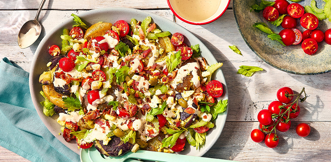 Overhead shot of the Canadian-Caesar Smashed potatoes in a platter with cherry tomatoes on the side.