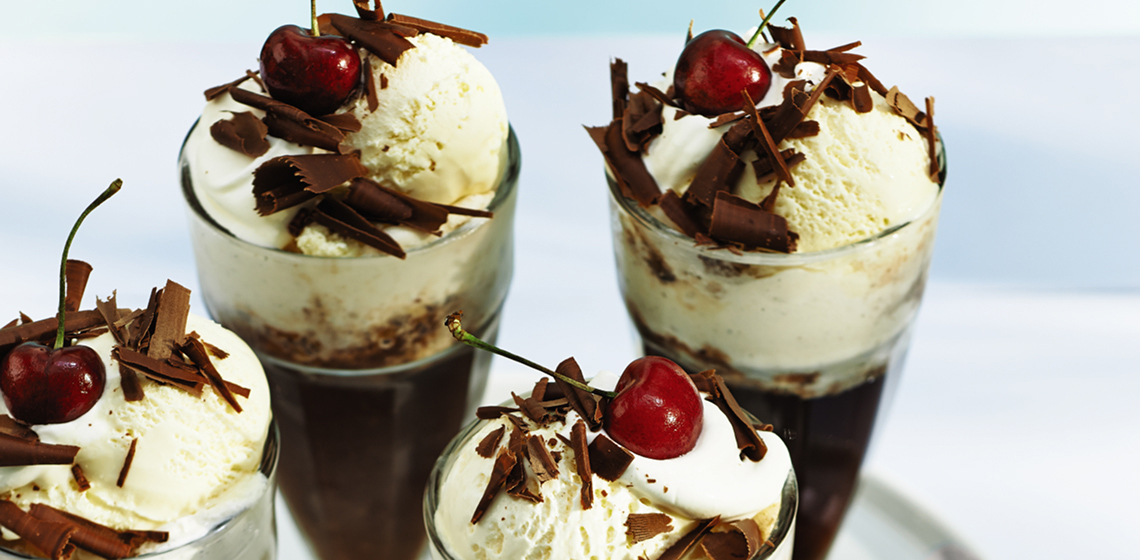 Four cherry root beer and bourbon floats in tall glasses on a white serving tray.