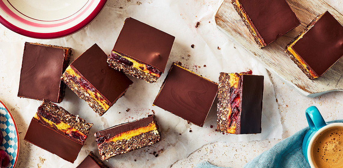Eight nanaimo bars with fresh cherries in middle