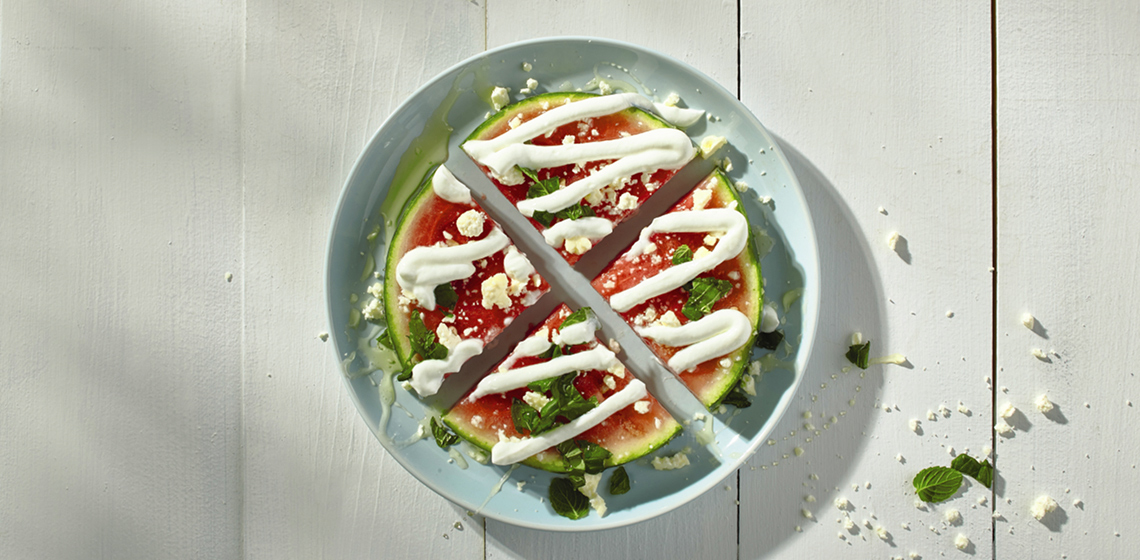 Overhead shot of savoury watermelon pizza on a blue plate.