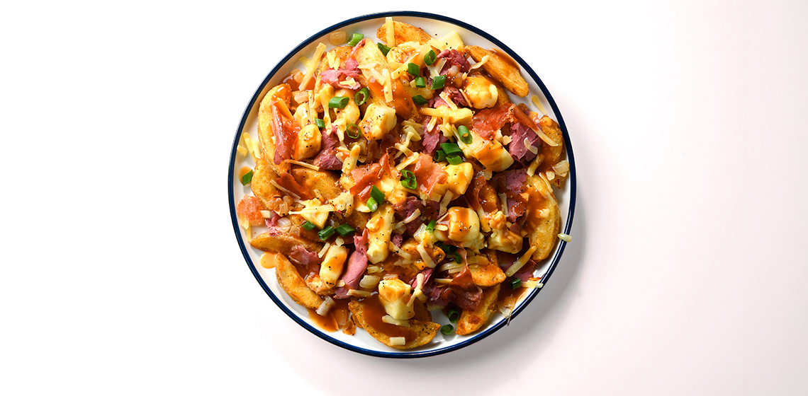 Green rimmed bowl filled with Montreal Smoked Meat Poutine